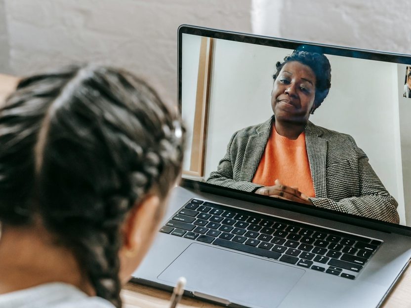 A child using a laptop for an online tutoring lesson with a teacher visible on screen